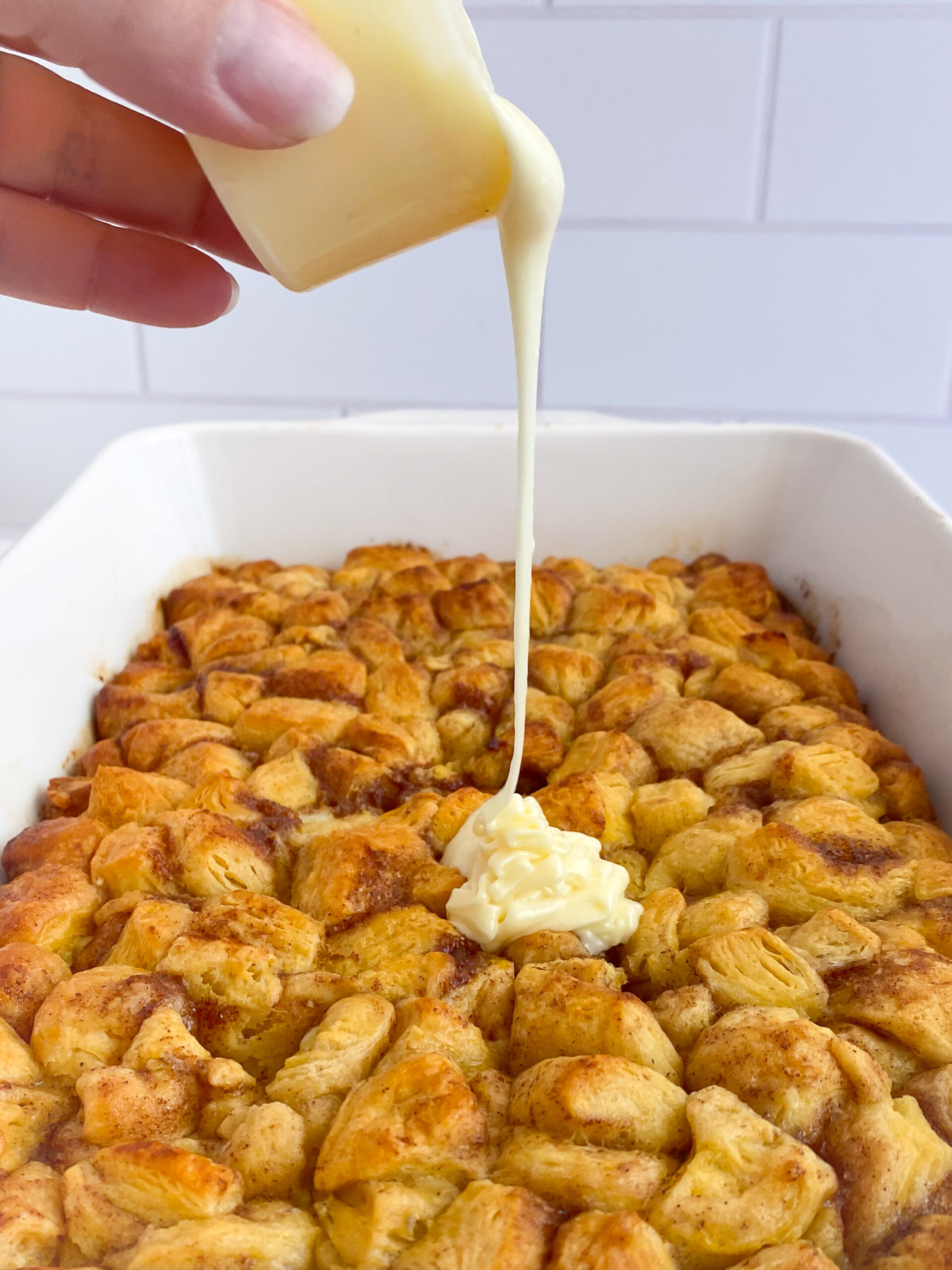 Frosting being poured over cinnamon roll casserole