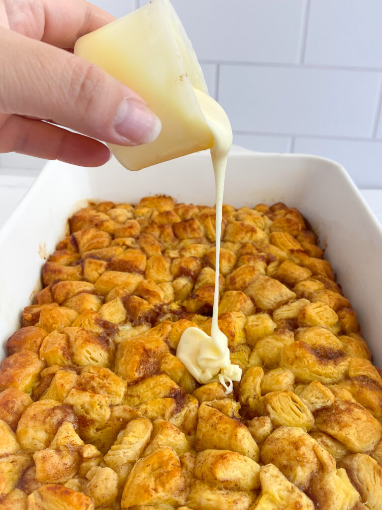 pouring the frosting over the cinnamon roll casserole