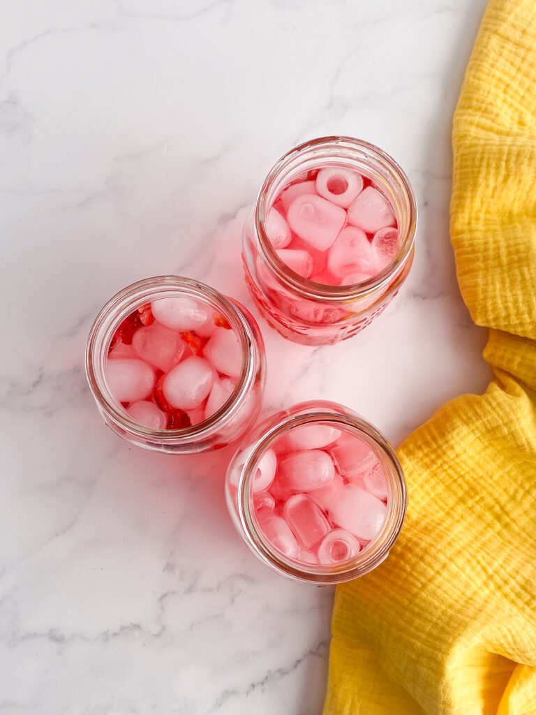 three glass jars on countertop with and pink drink juice