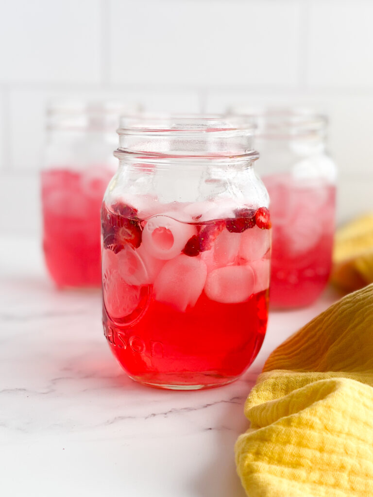 pink drink with just the juice and freeze dried strawberries on a white countertop