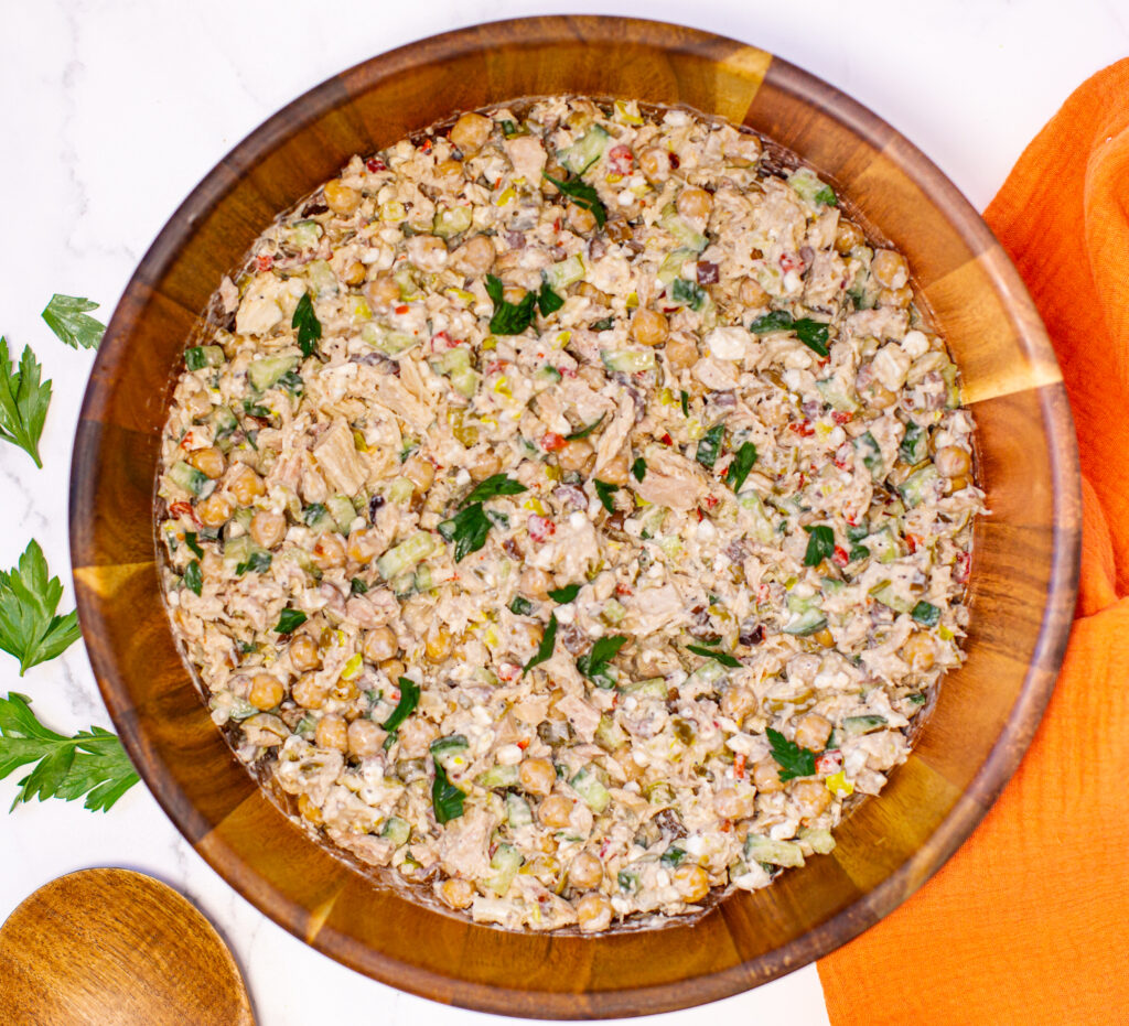 a wooden bowl full of tuna salad on a white marble countertop