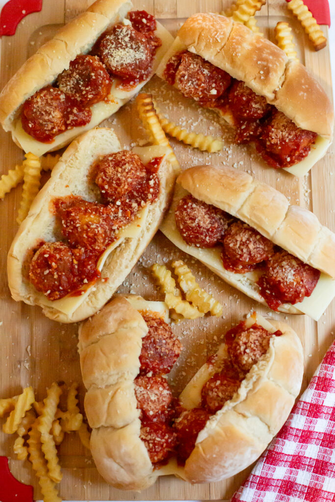 meatball subs and french fries on a cutting board