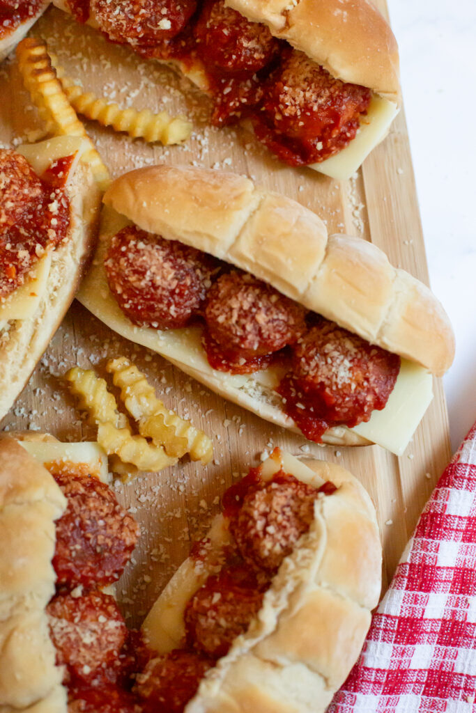 meatball subs and french fries on a cutting board
