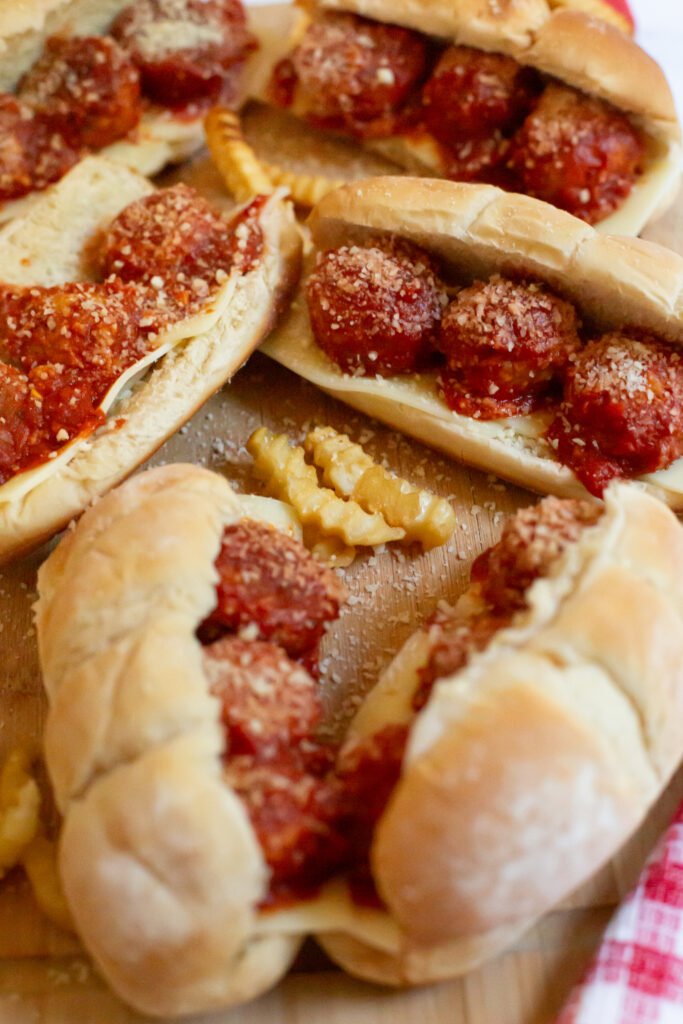 meatball subs and french fries on a cutting board