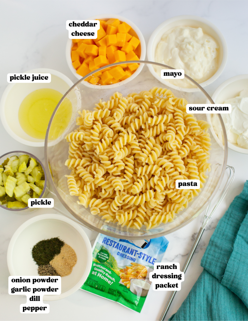 ingredients for a pasta salad in bowls on a white countertop