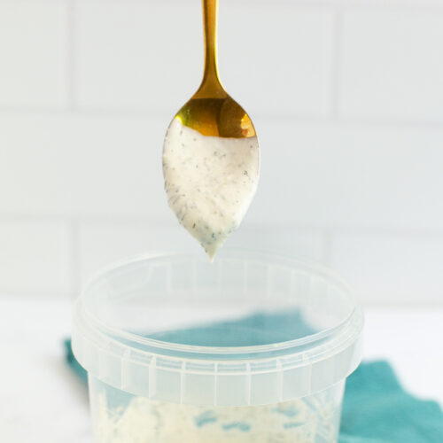 spoon with ranch hovering over a food storage container