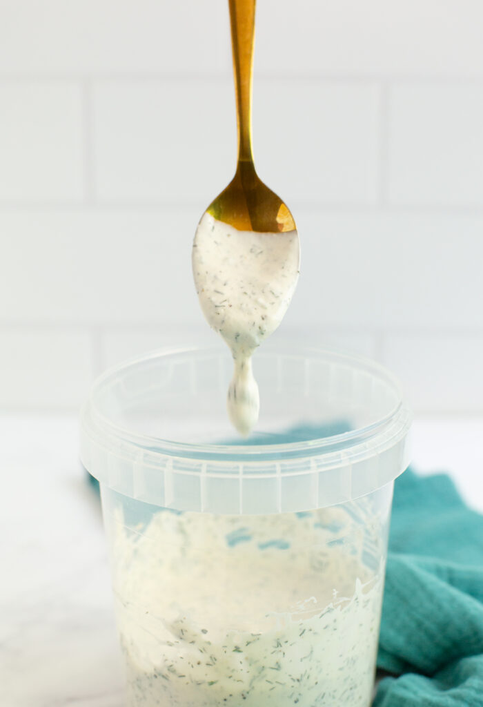 spoon hovering over a container full of homemade ranch
