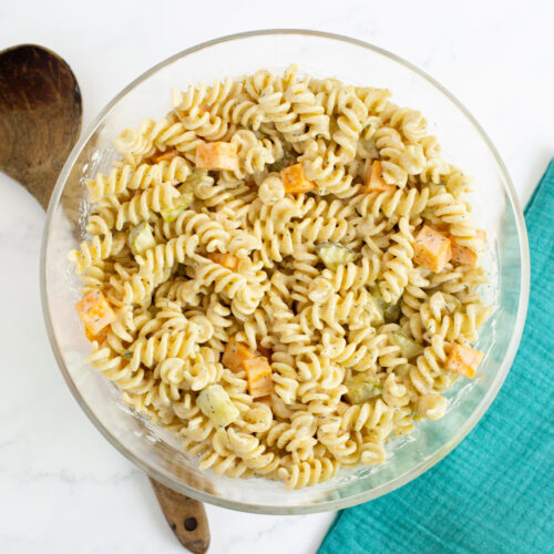 pasta salad with pickles and cheese in a bowl on a white countertop