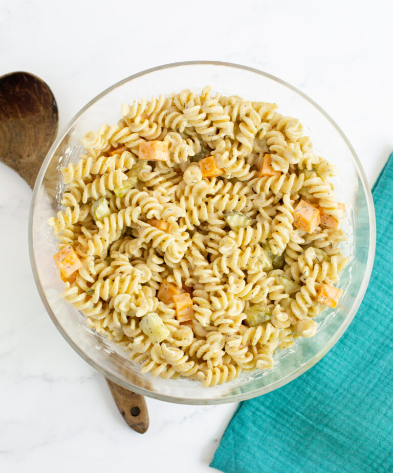 pasta salad with pickles and cheese in a bowl on a white countertop