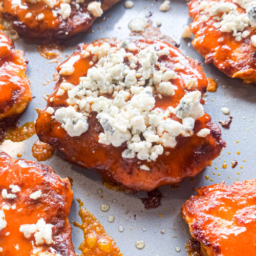buffalo chicken burgers in a skillet topped with blue cheese