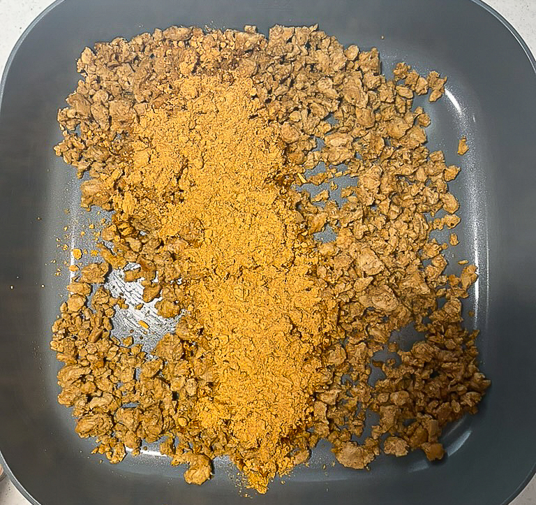 ground meat with a packet of chili seasoning on top 