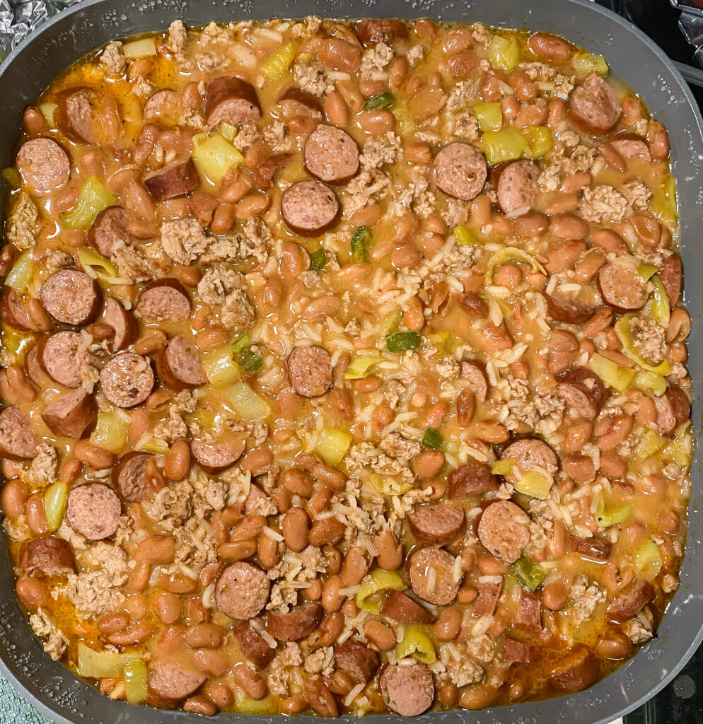 beans, meat, and rice are cooking in a skillet