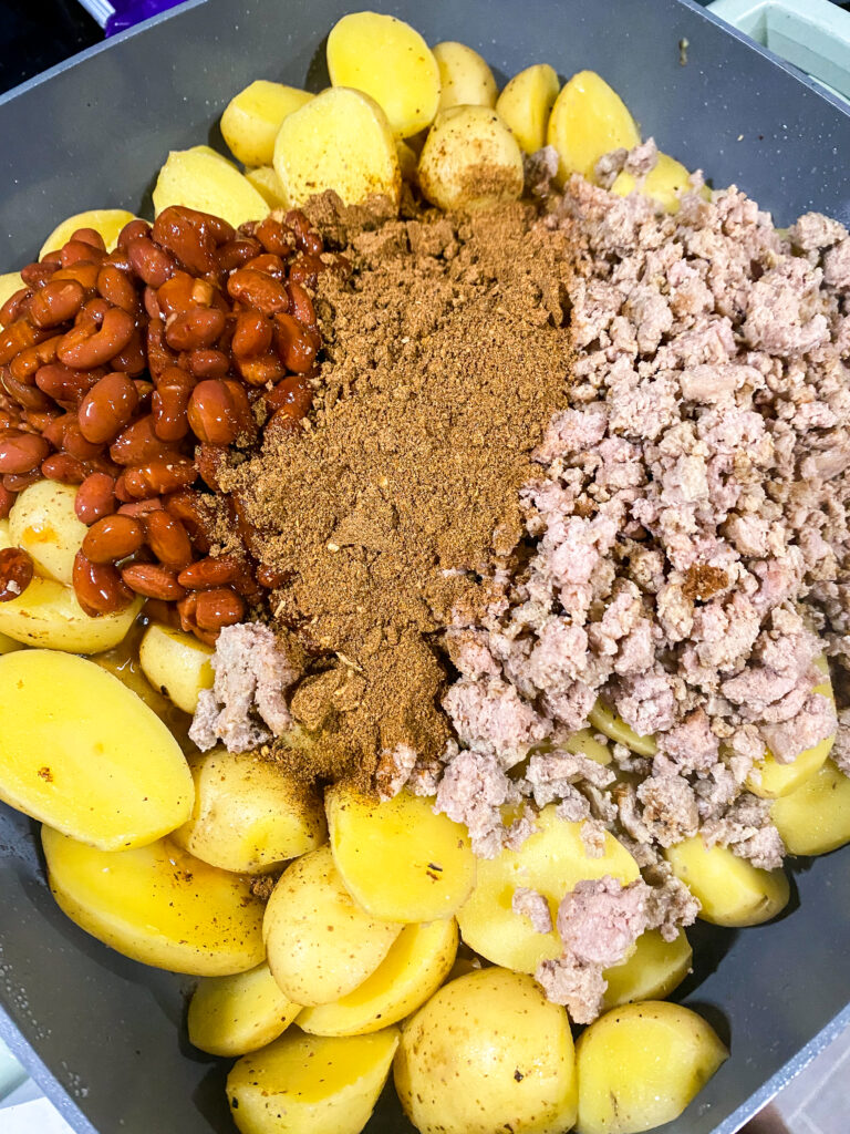 halved potatoes, beans, ground meat, and chili seasoning in a skillet.