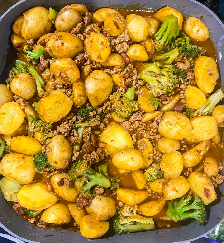 the potatoes, ground meat, chili beans, chili seasoning, and broccoli all stirred together in a skillet