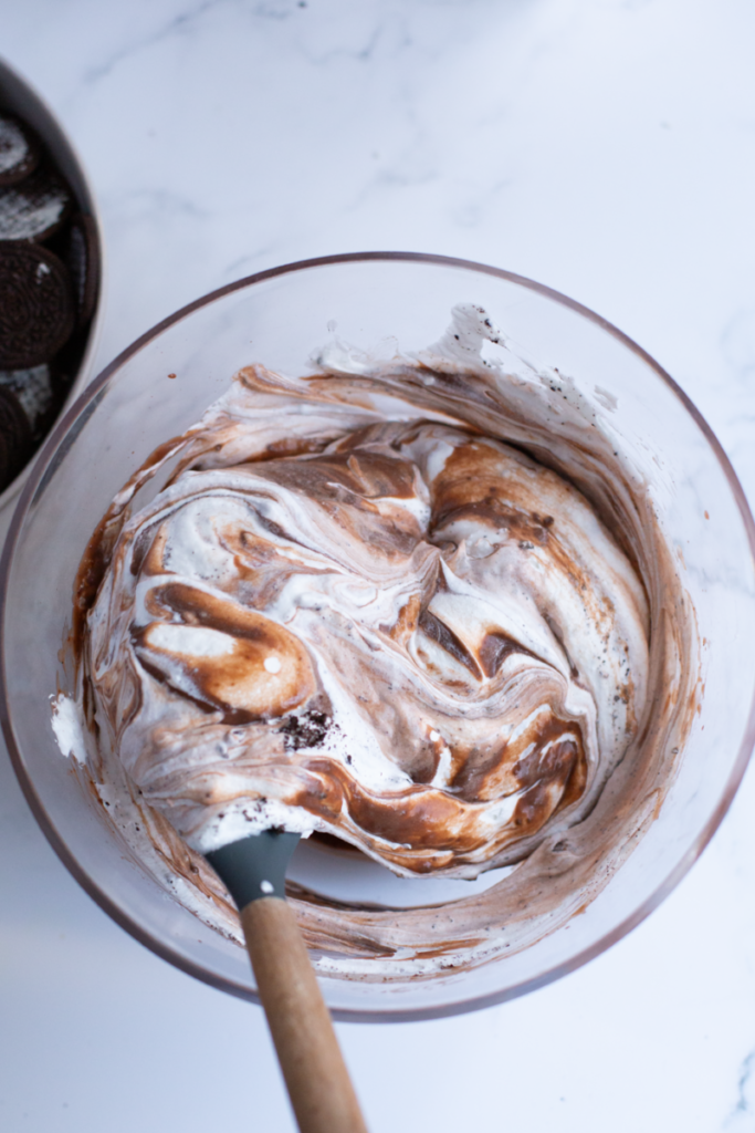 stirring the pudding and cool whip and oreo cookie mixture together