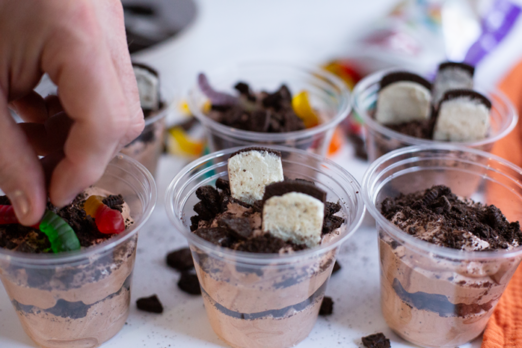 hand placing worm in a dirt pudding cup