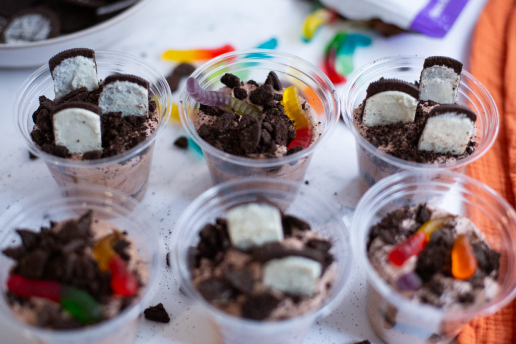 the dirt and worms pudding cups ready with tombstone shaped oreos and gummy worms for halloween