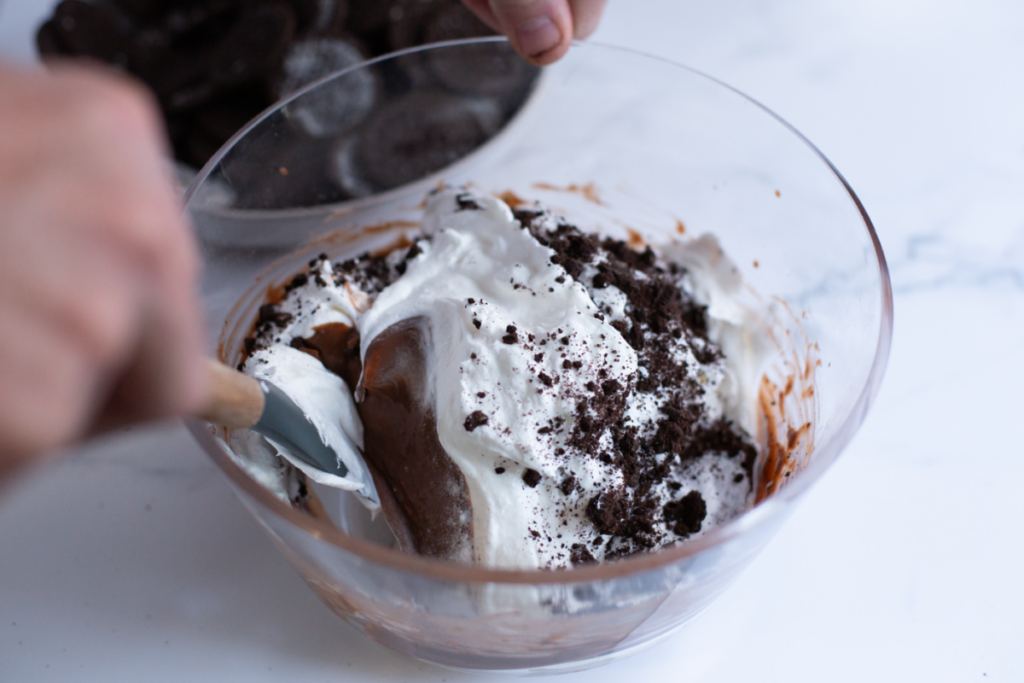 cool whip and pudding and oreo cookie crumbs in a bowl