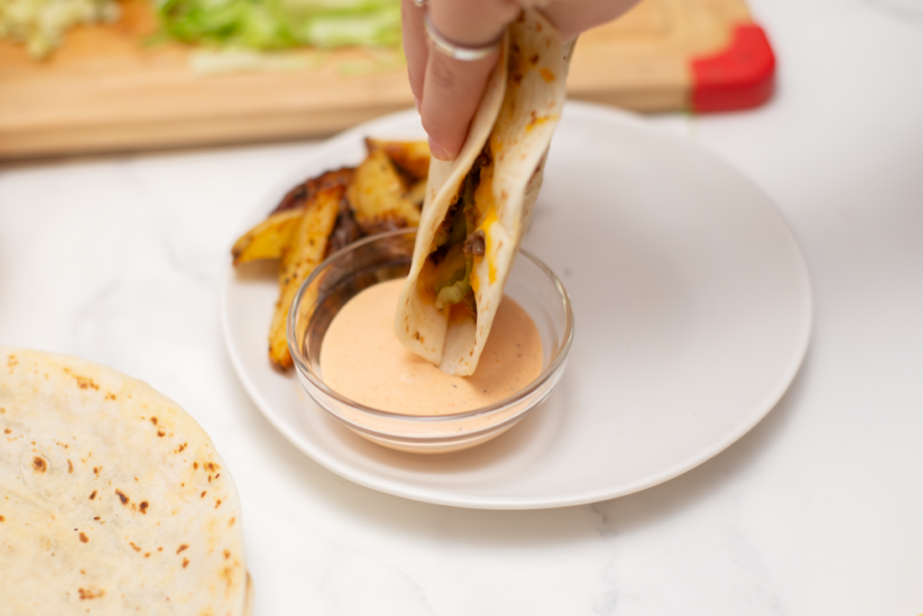 the quesadilla burger is being dipped in the burger sauce 