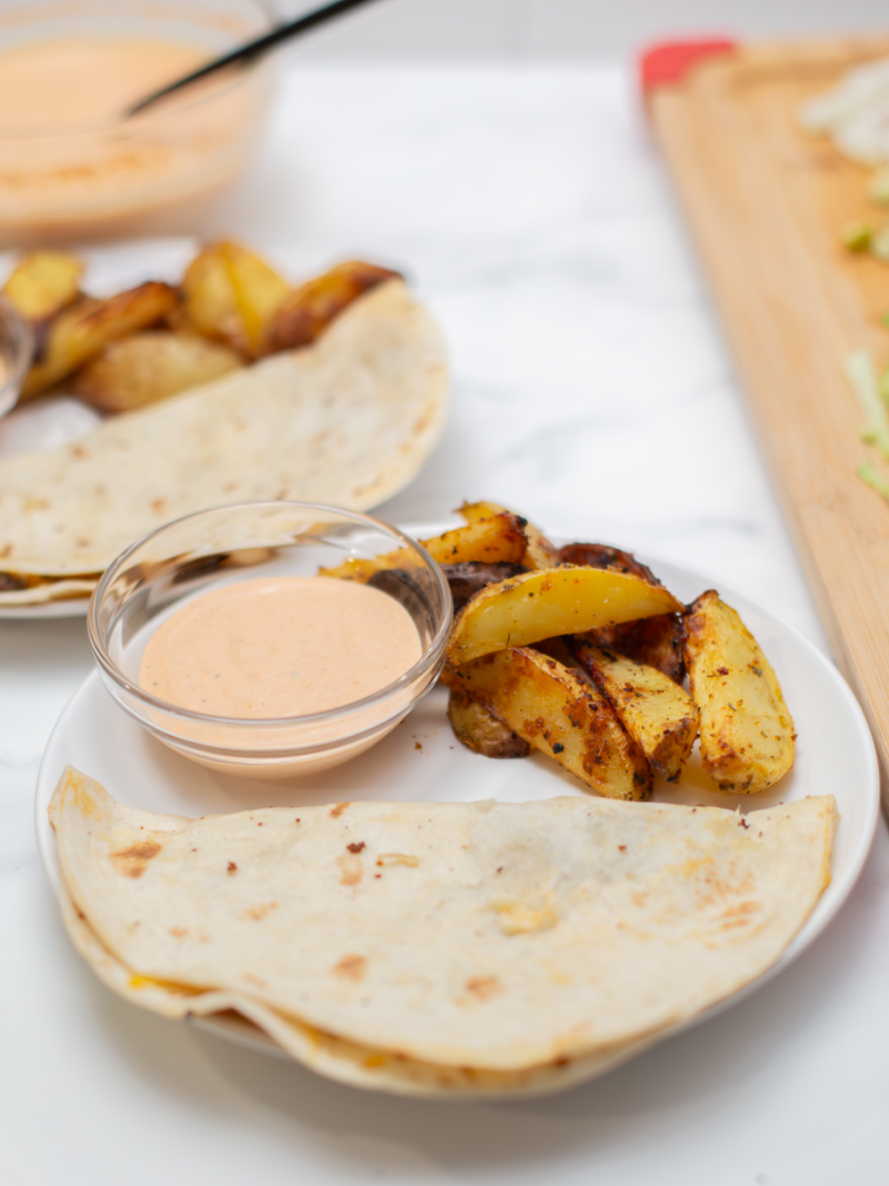 quesadilla burger ona. white place plate with potatoes and dipping sauce