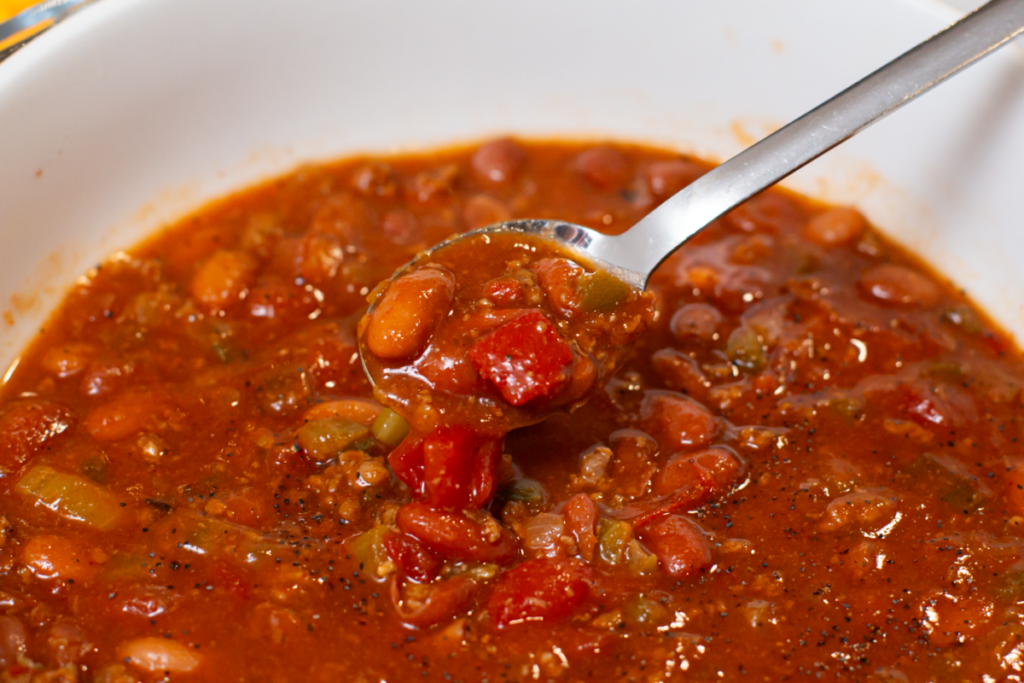 a spoon full of chili in a white bowl of chili