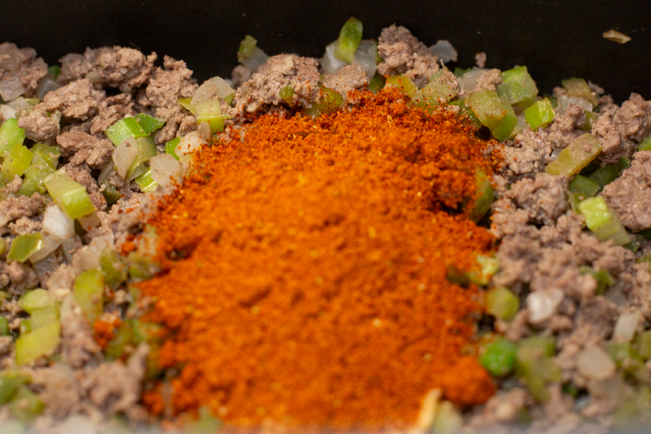 cook browned ground beef with seasoning, onions, bell peppers, and celery in a pot