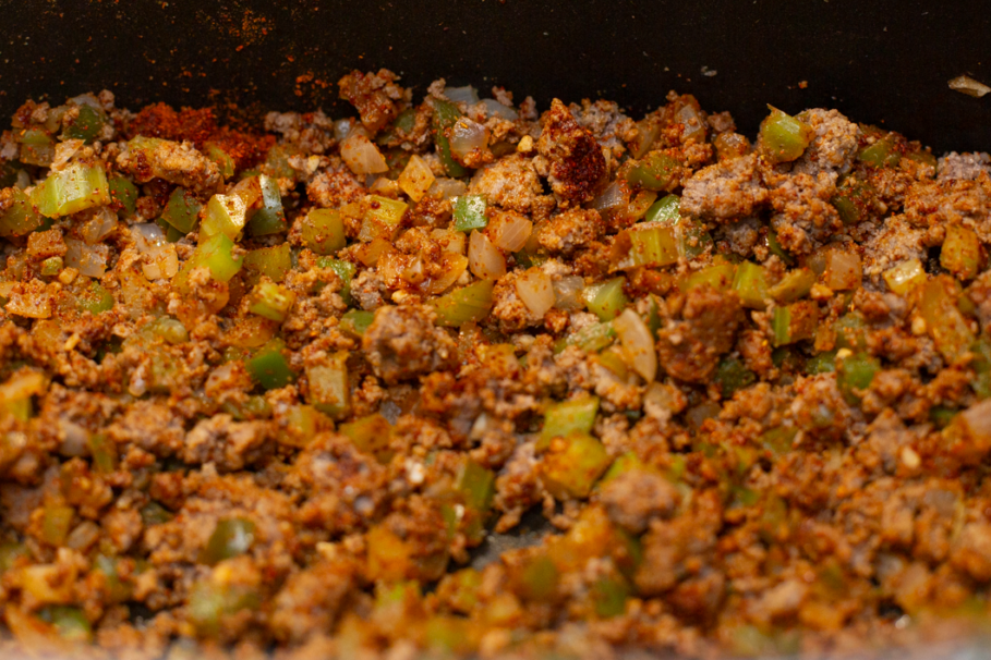 seasoned browned ground beef with onions, bell peppers, and celery in a pot