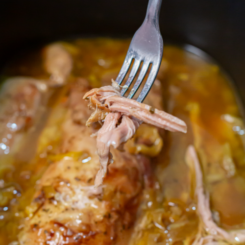mississippi pork loin on a fork above a slow cooker