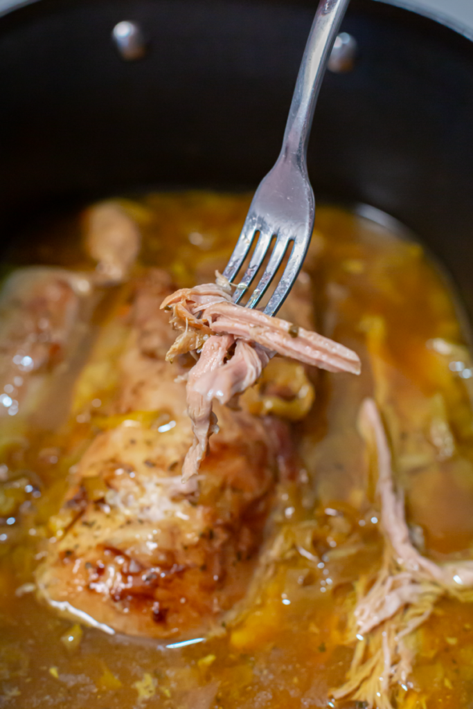 mississippi pork roast on a fork above the slow cooker