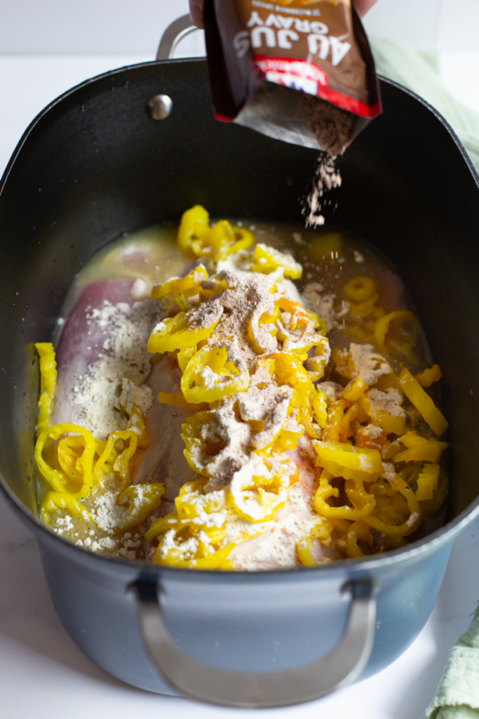 au just packet mix being poured onto raw pork loin in a slow cooker