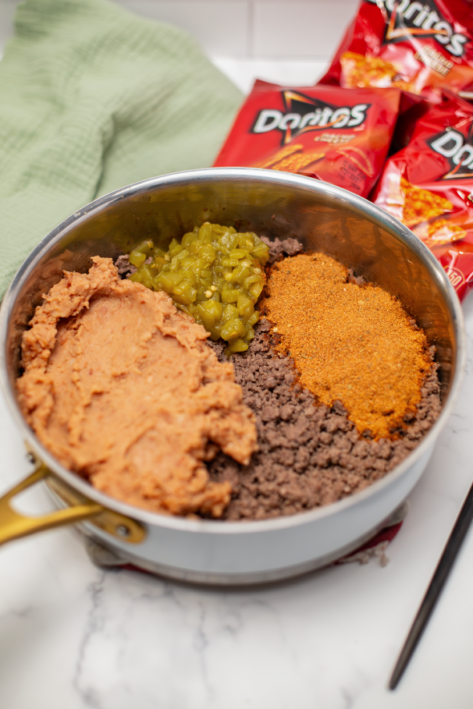 meat beans green chiles and taco seasoning in a skillet on a white counter