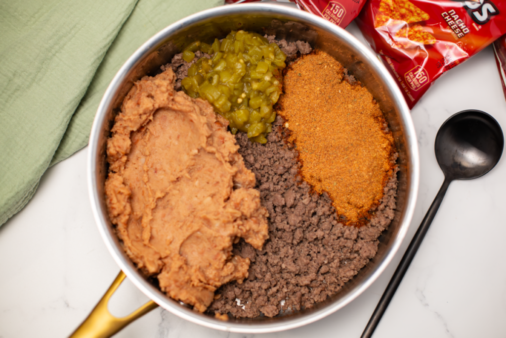 ground beef, refried beans, green chiles, taco seasoning in a skillet on a white counter