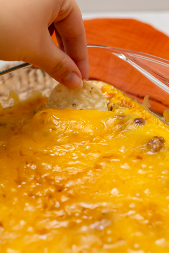 hand dipping a chip in the cooked dip