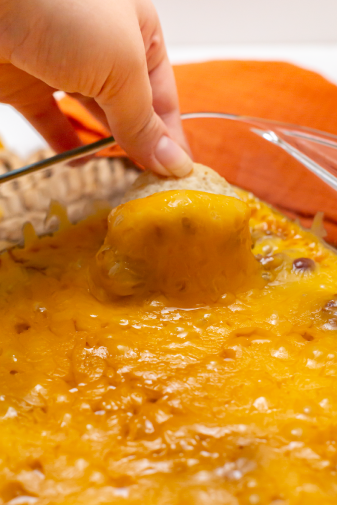 a picture of a chip being dipped into the cheese