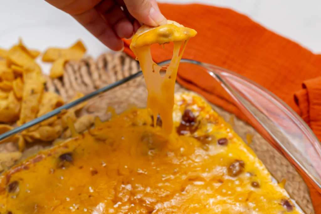 Chili cheese dip on a chip showing the cheese pull on a chip 