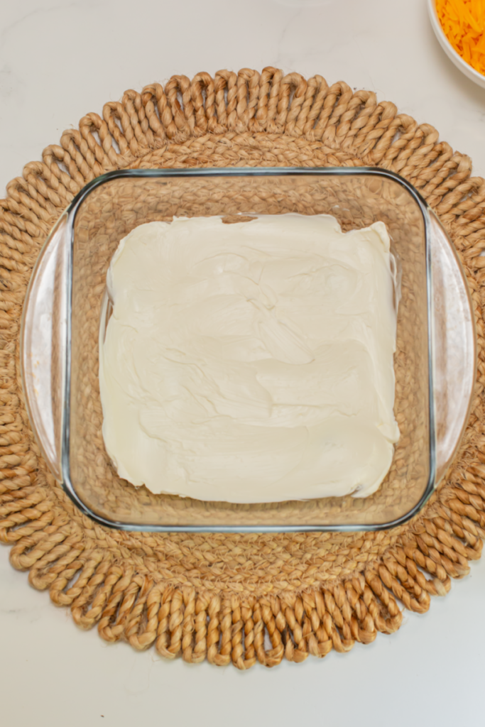 cream cheese spread into the bottom of a glass casserole dish