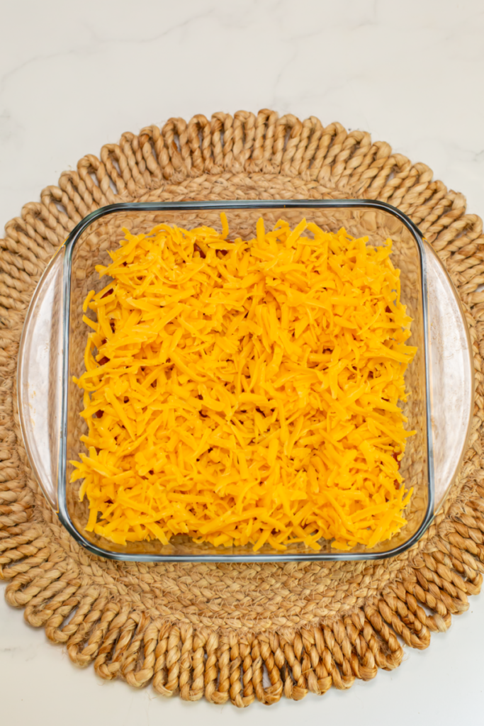 shredded cheddar into the bottom of a glass casserole dish