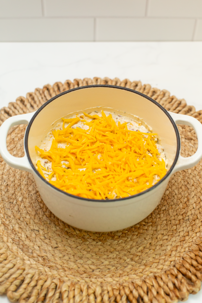 a crock of creamy cheddar jalapeno bacon ranch dip topped with the shredded cheddar cheese