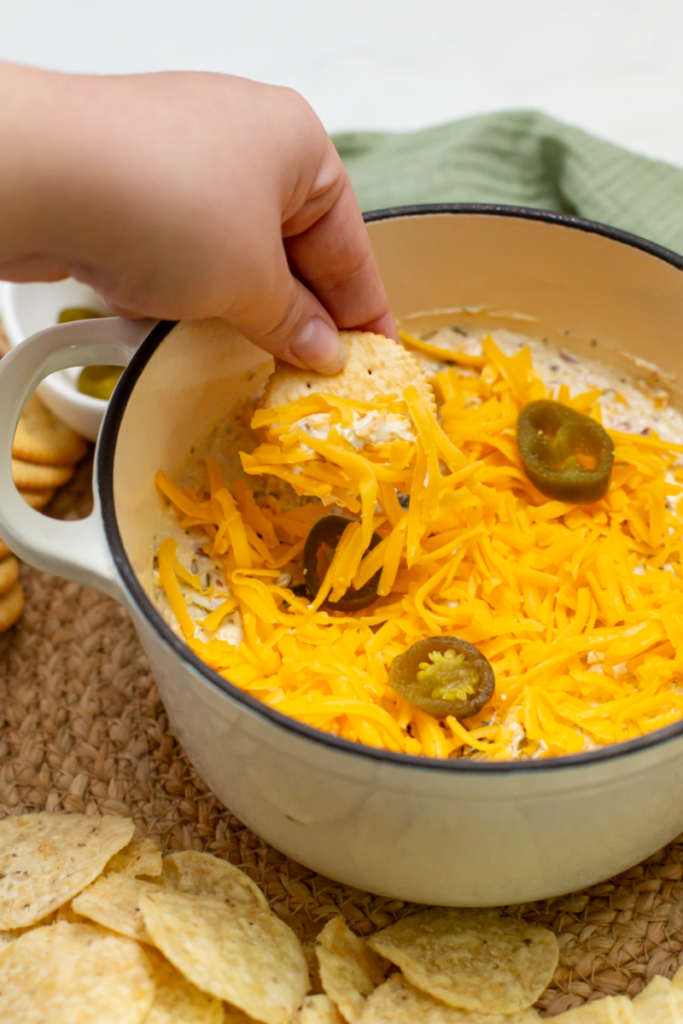 hand dipping cracker in dip