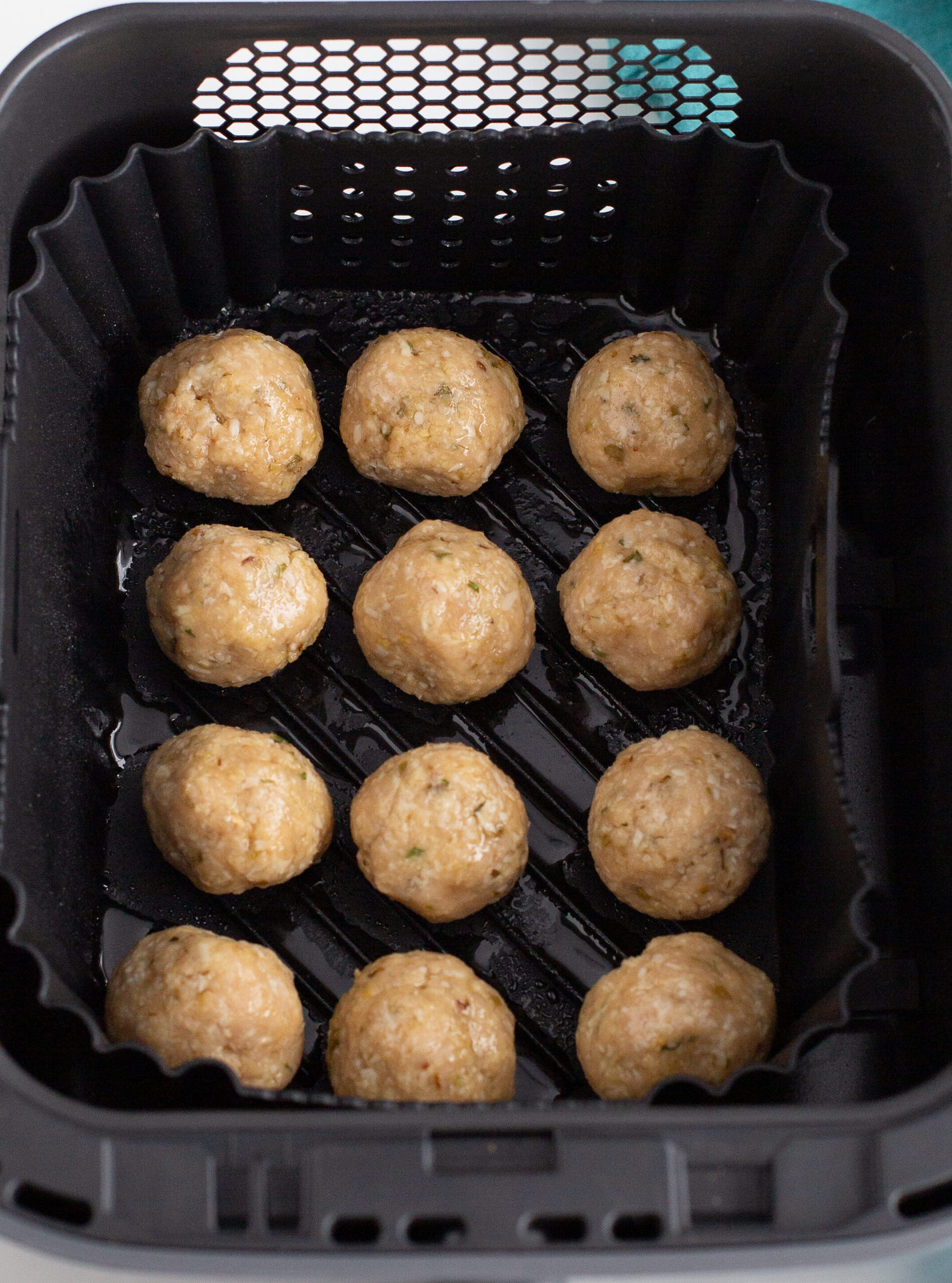 12 meatballs made and aligned in a air fryer basket 