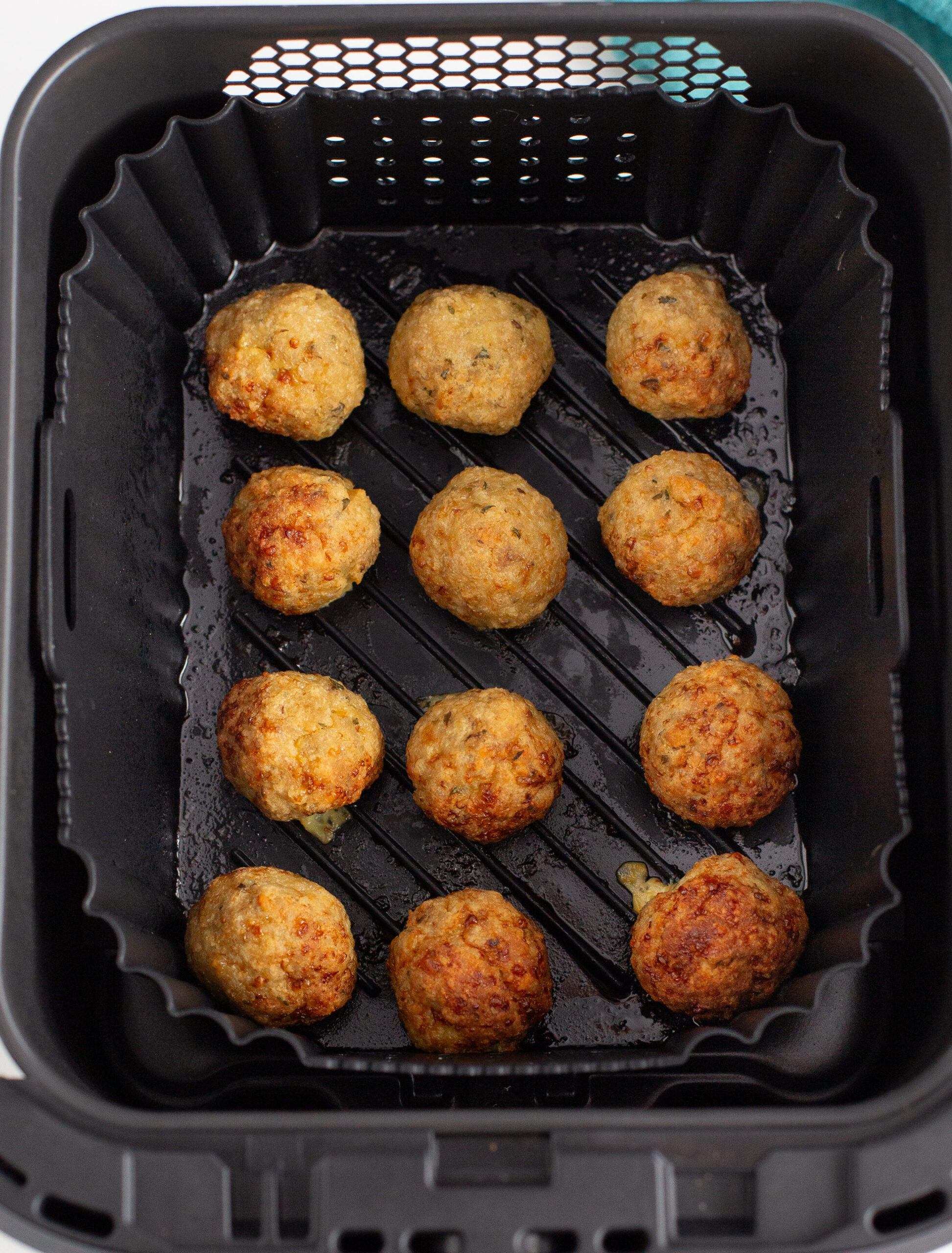 all 12 chicken meatballs cooked in an air fryer basket 