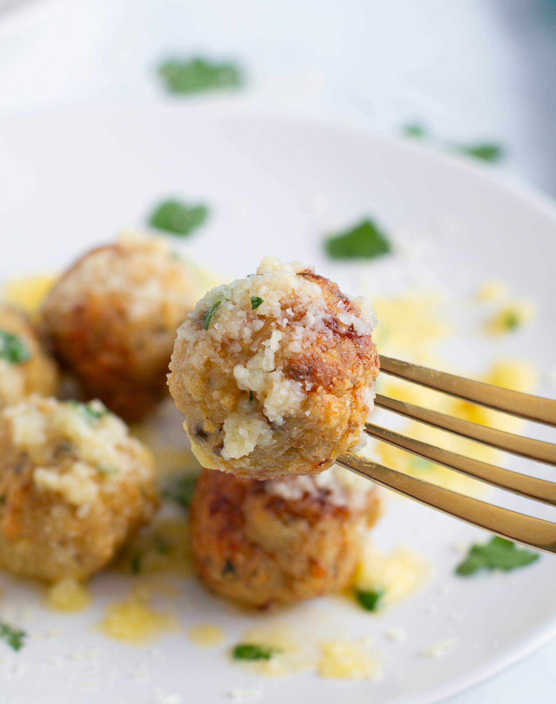 chicken meatball on a fork in front of a white plate