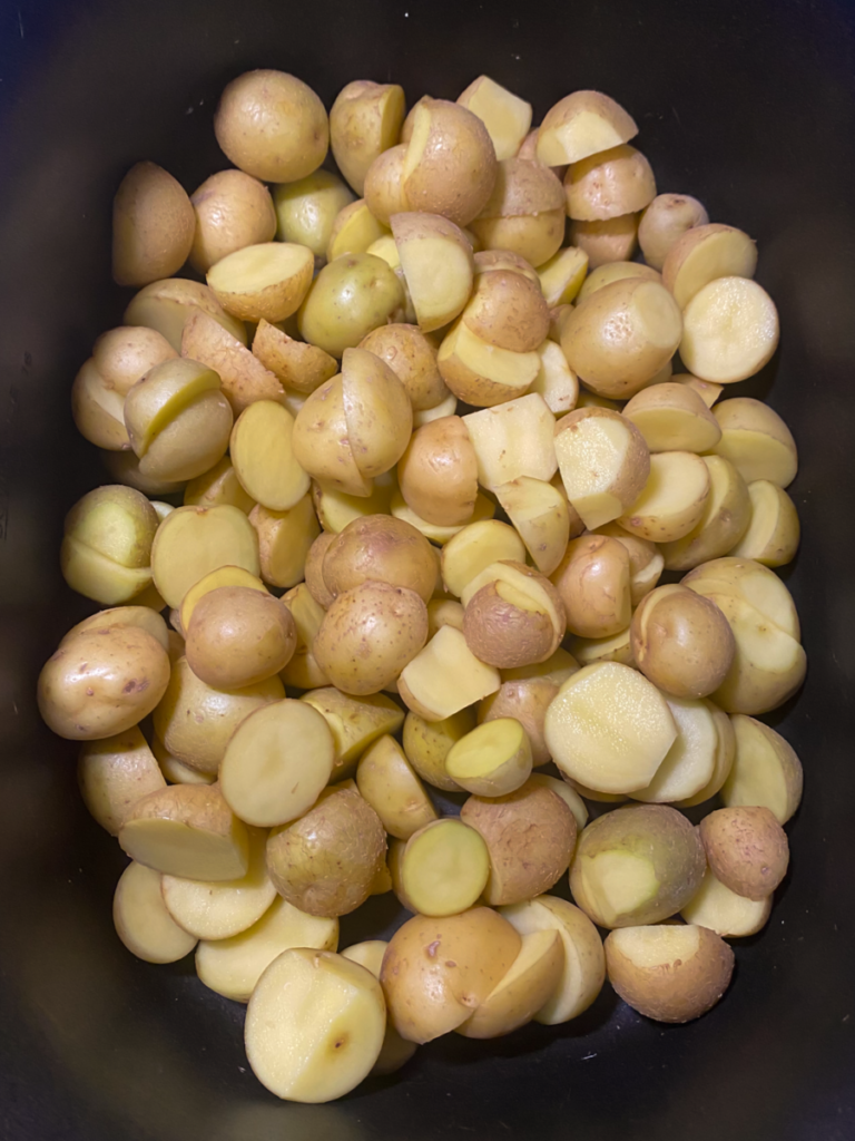 halved baby potatoes in the bottom of a slow cooker