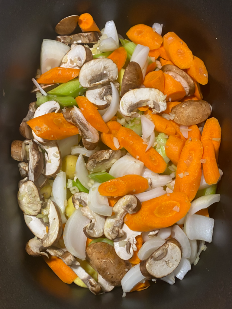 carrots, celery, mushrooms, onions, and garlic on top of the halved baby potatoes in the slow cooker