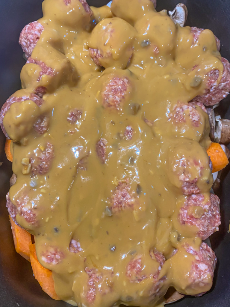 The sauce on top of the meatballs evenly dispersed in the slow cooker. 
